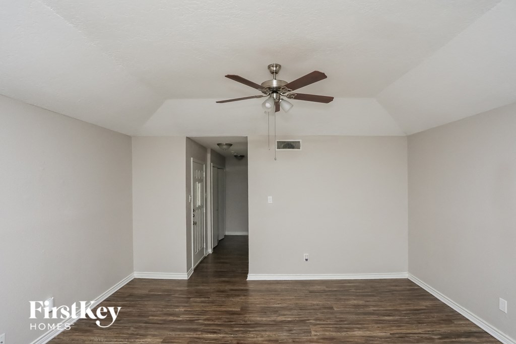 A room with a ceiling fan and wooden floors.