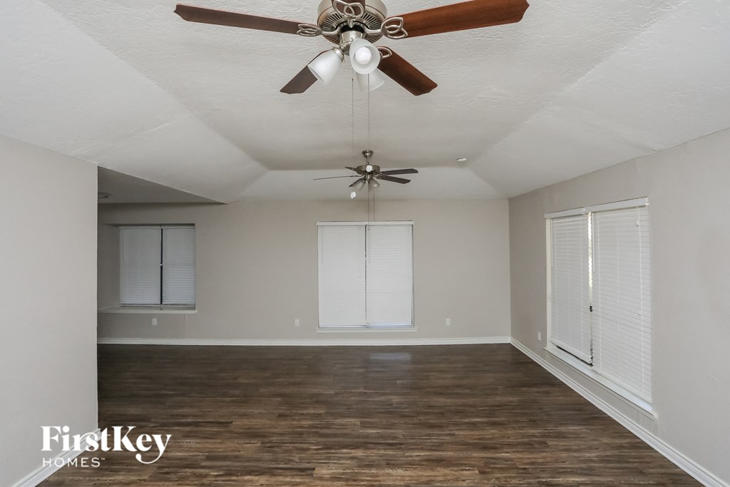 A room with a ceiling fan and wooden floors.
