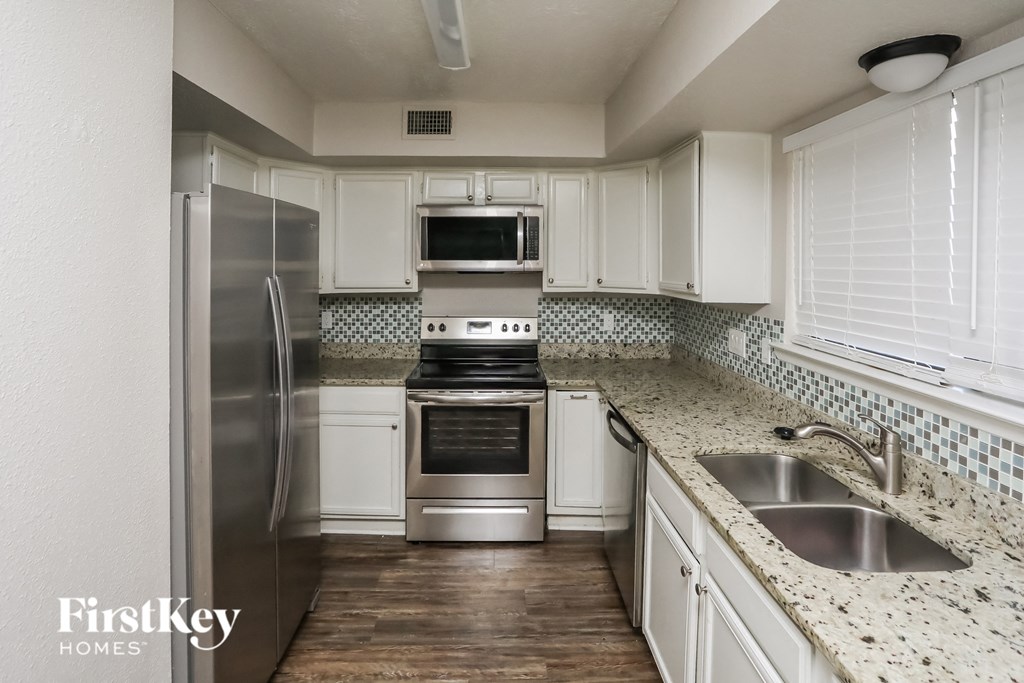 A kitchen with a stainless steel refrigerator, oven, and sink.
