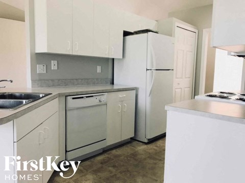 A kitchen with white cabinets and appliances, and a FirstKey Homes logo.