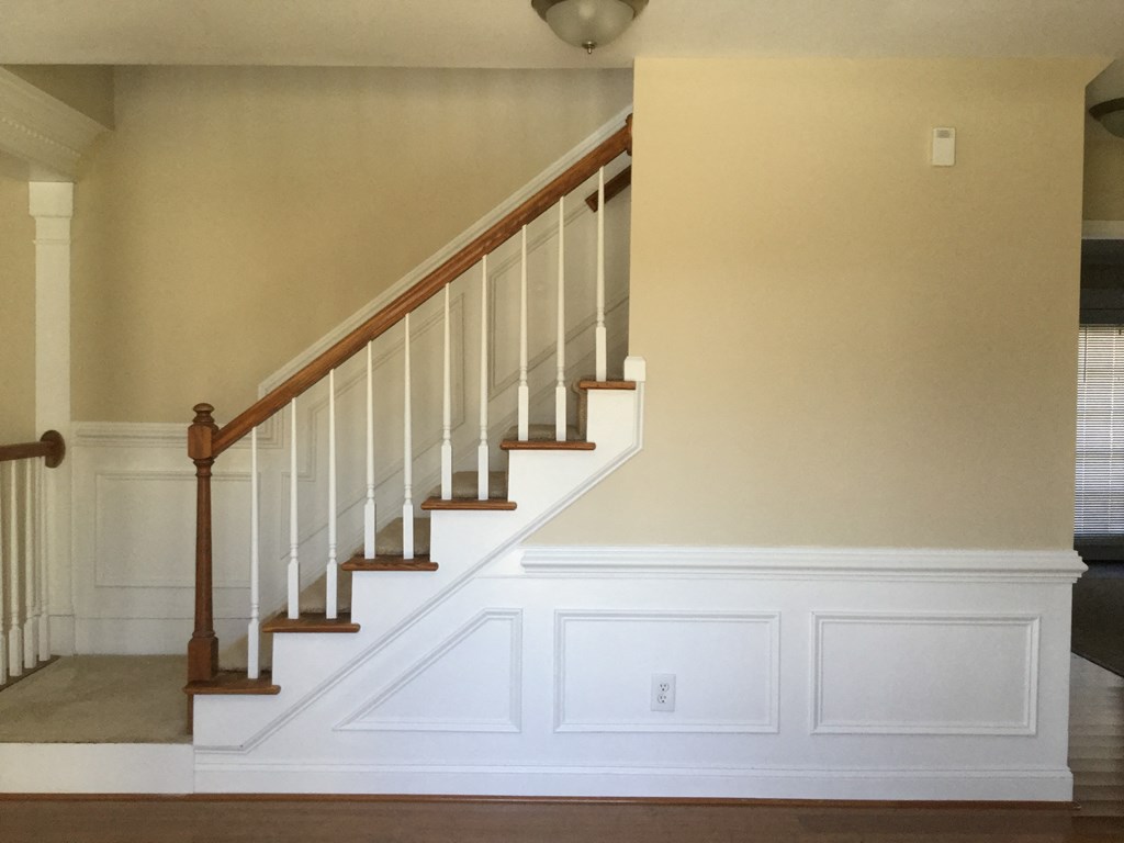 a staircase in a home with white walls and a wooden railing