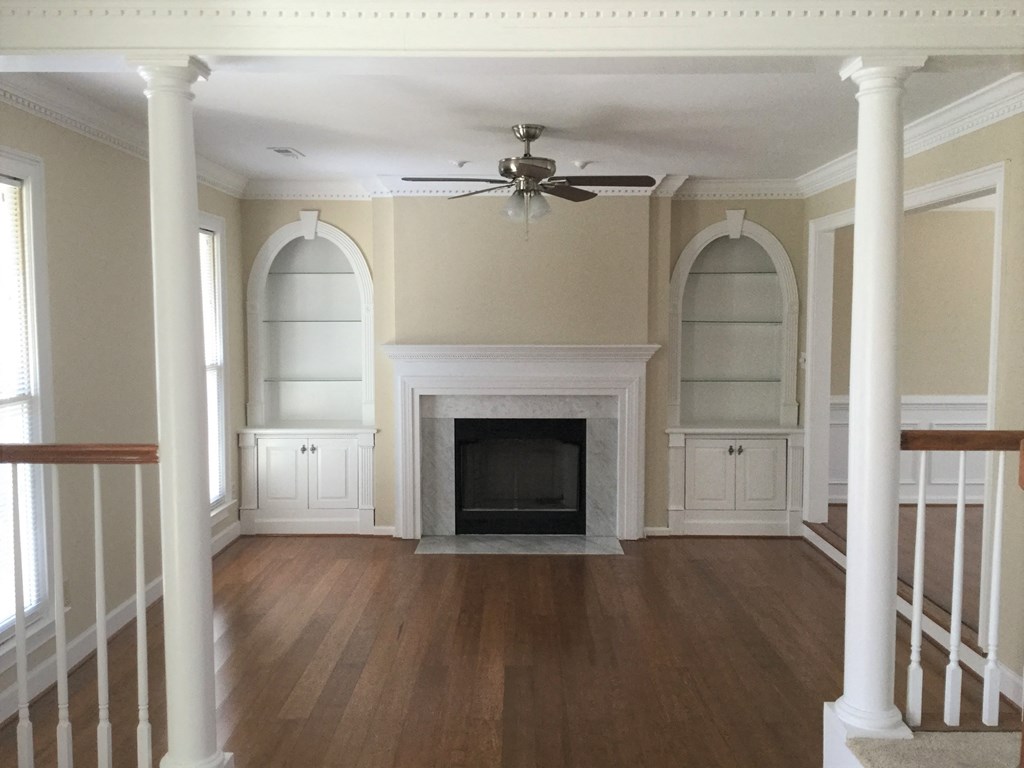 an empty living room with a fireplace and a ceiling fan