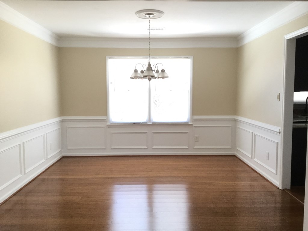 an empty dining room with wood floors and a window