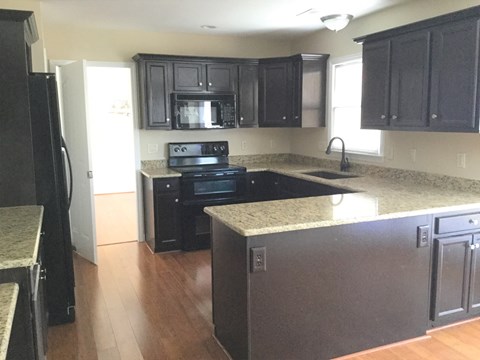 an empty kitchen with black appliances and granite counter tops