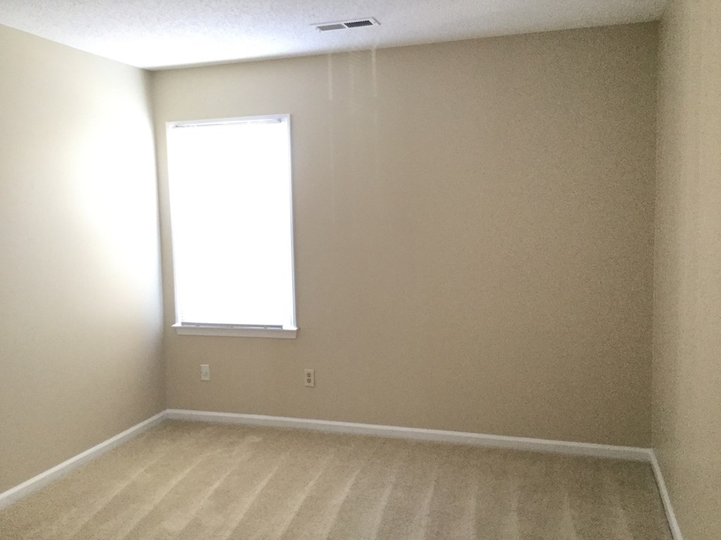 an empty room with a window and a wooden floor