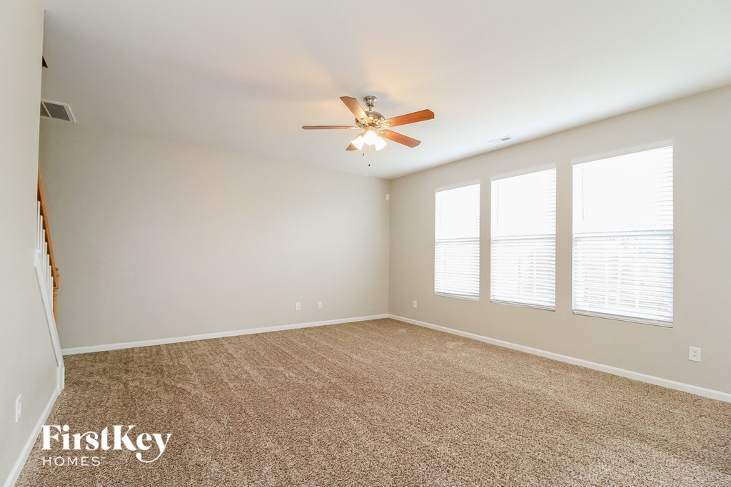 A spacious room with a ceiling fan and carpeted floor.