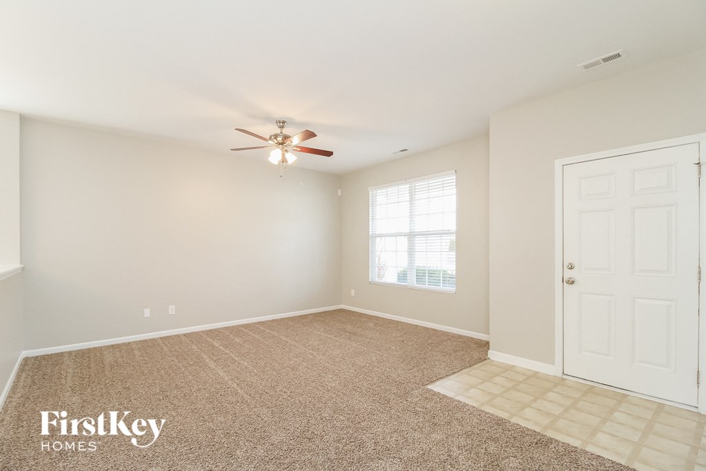 A room with a carpeted floor and a ceiling fan.