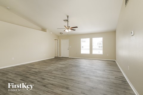 a spacious living room with white walls and a ceiling fan