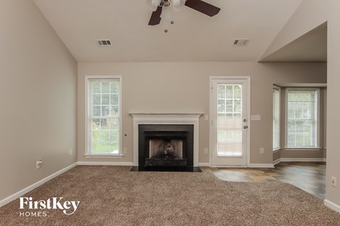 A living room with a fireplace and a fan on the ceiling.