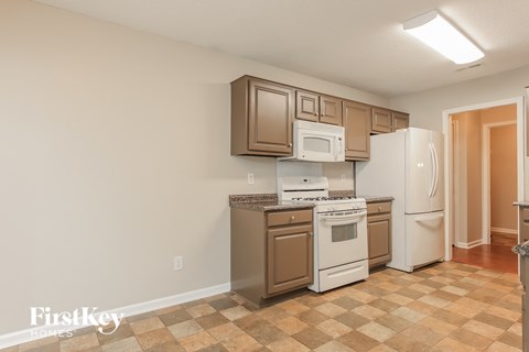 A kitchen with brown cabinets and white appliances.