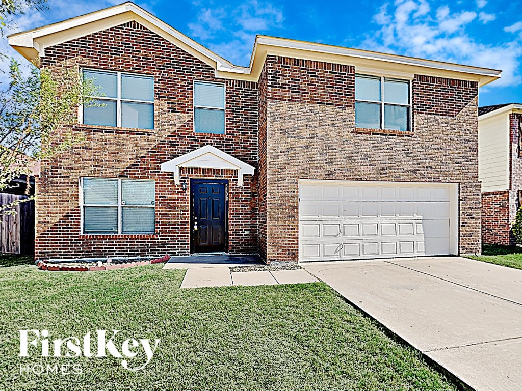 a brick house with a garage door and a lawn
