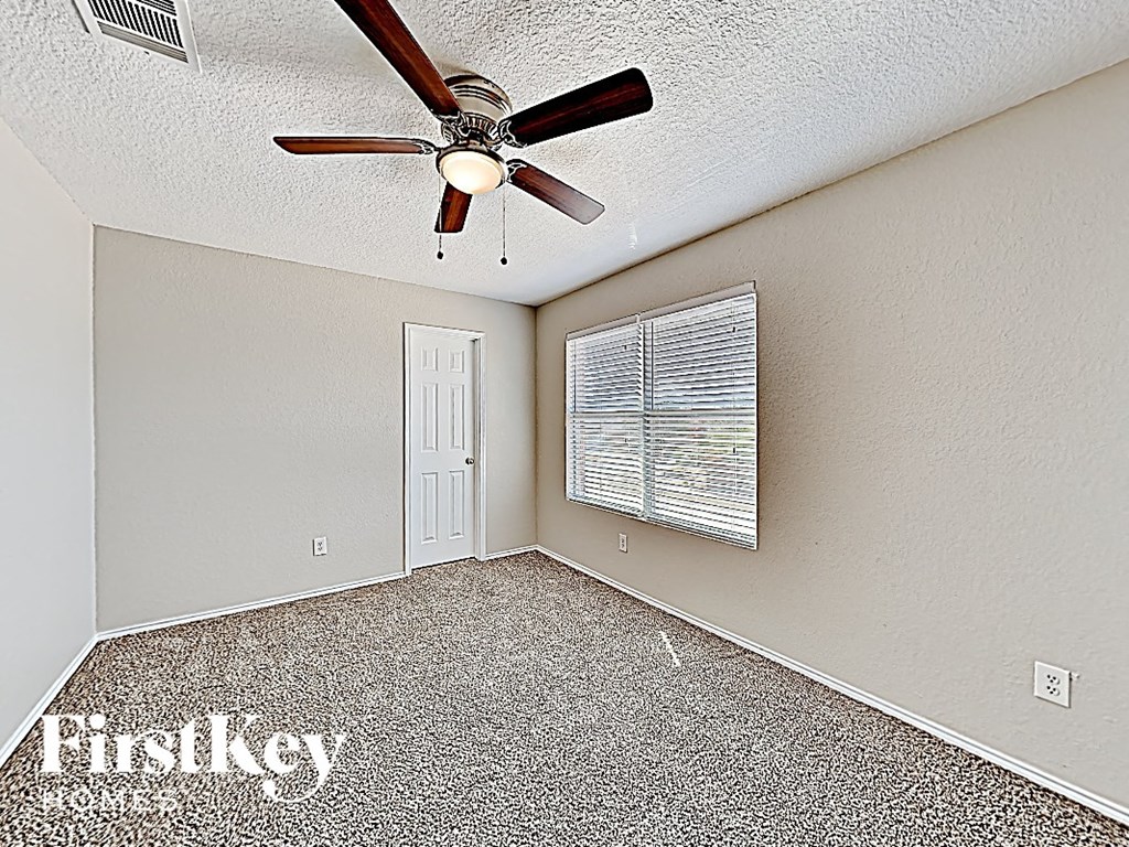an empty bedroom with a ceiling fan and a window