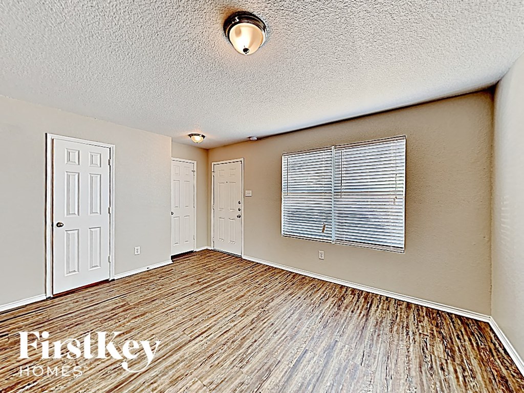 an empty living room with a wood floor and a window