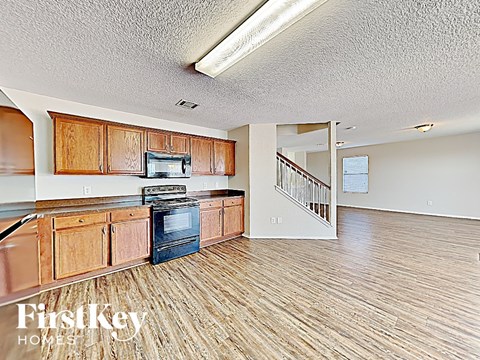 a kitchen and living room with wood floors and a staircase