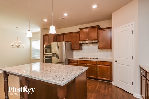 an updated kitchen with granite countertops and wooden cabinets