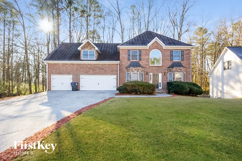 a brick house with white garage doors and a green lawn