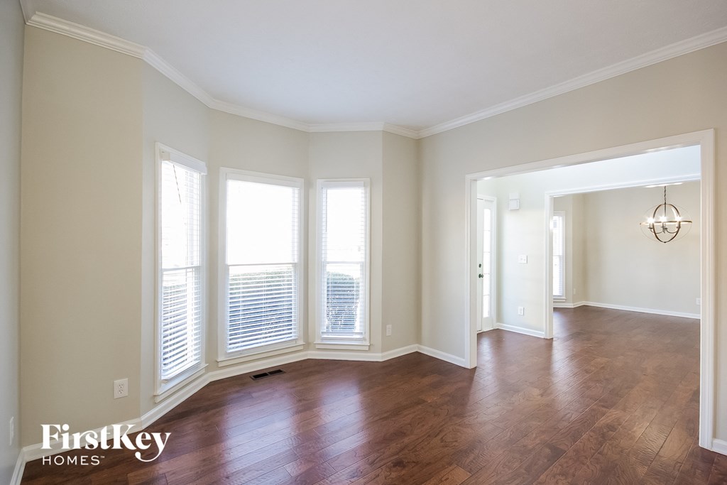 an empty living room with wood floors and large windows