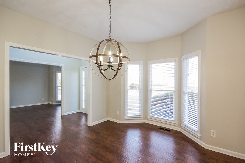 an empty living room with large windows and a chandelier