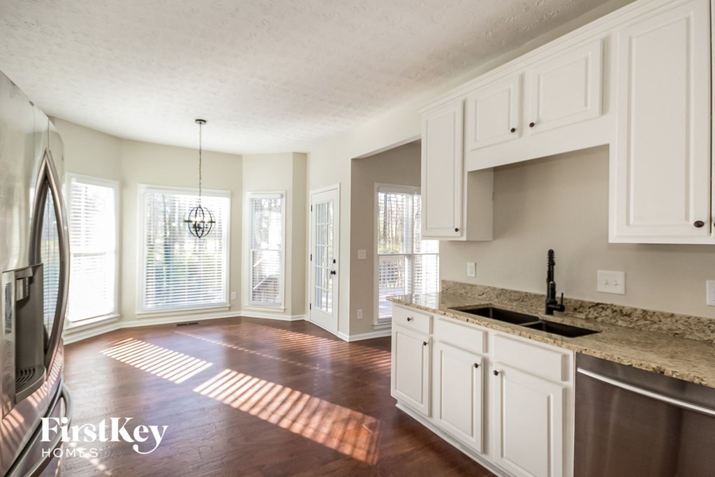an empty kitchen with white cabinets and a counter top and a sink