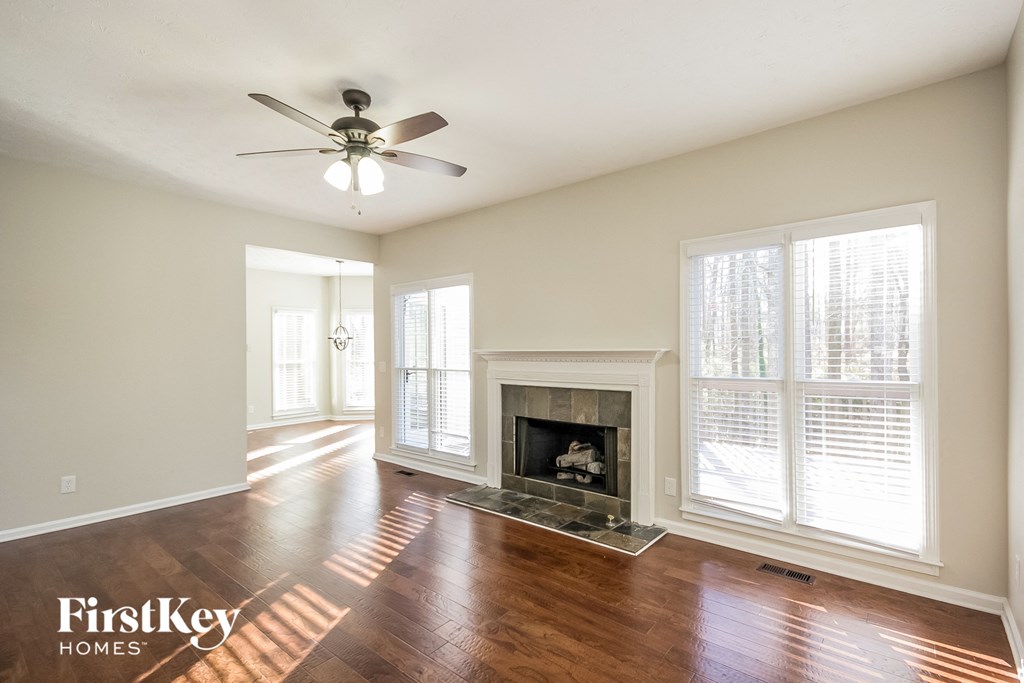 an empty living room with a fireplace and a ceiling fan