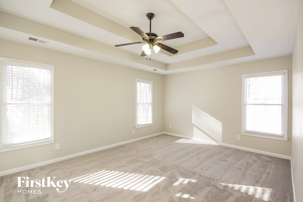 an empty living room with a ceiling fan and two windows