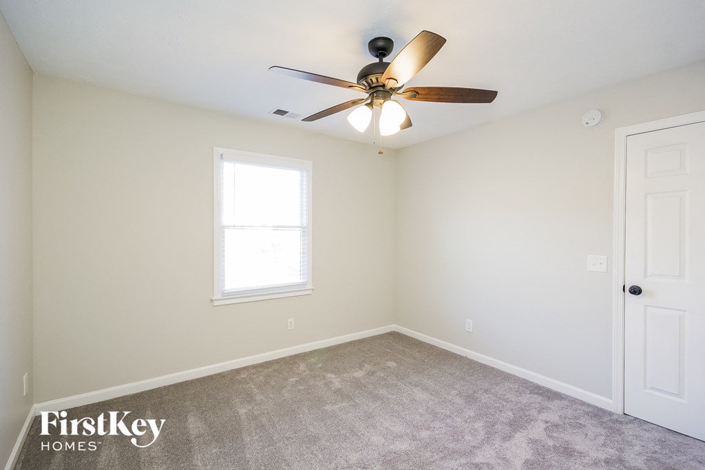 a bedroom with white walls and a ceiling fan and a white door