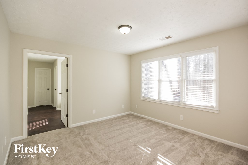 the spacious living room with a door to the hallway and a large window