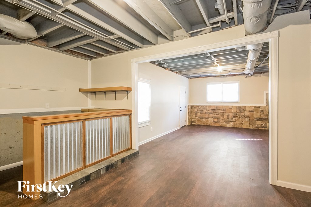 the living room and dining room of a house with a wood floor and exposed ceilings