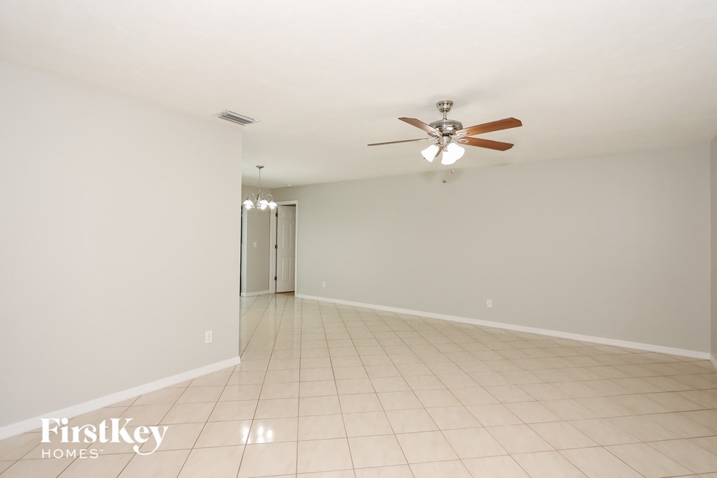 a empty living room with a ceiling fan and a tiled floor