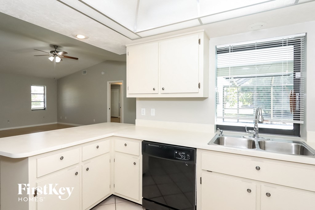a kitchen with white cabinets and a sink and a window