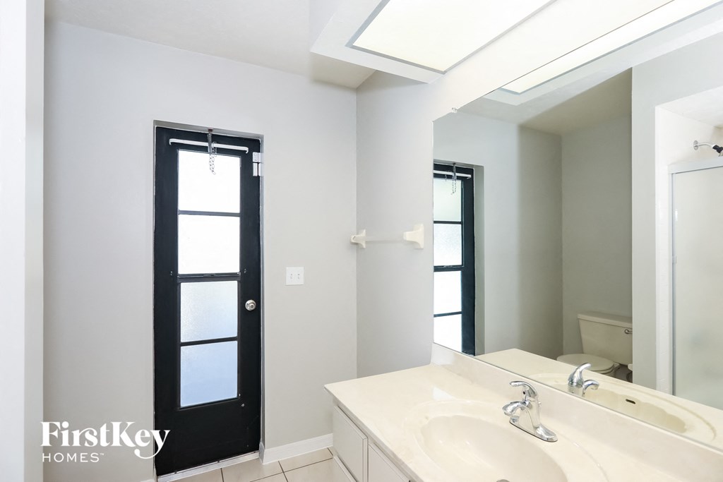 a white bathroom with a sink and a mirror and a black door