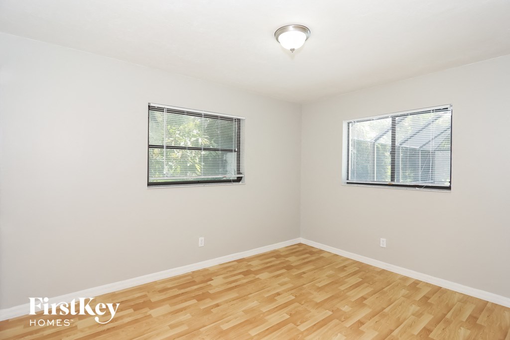 a spacious living room with wood floors and two windows