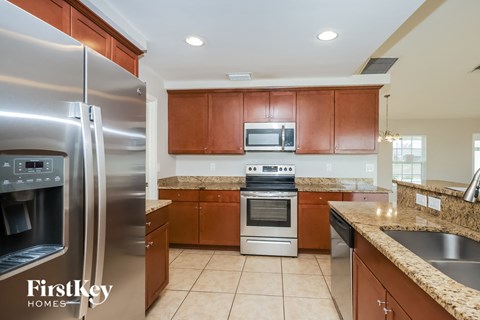 A kitchen with a stainless steel refrigerator and wooden cabinets.