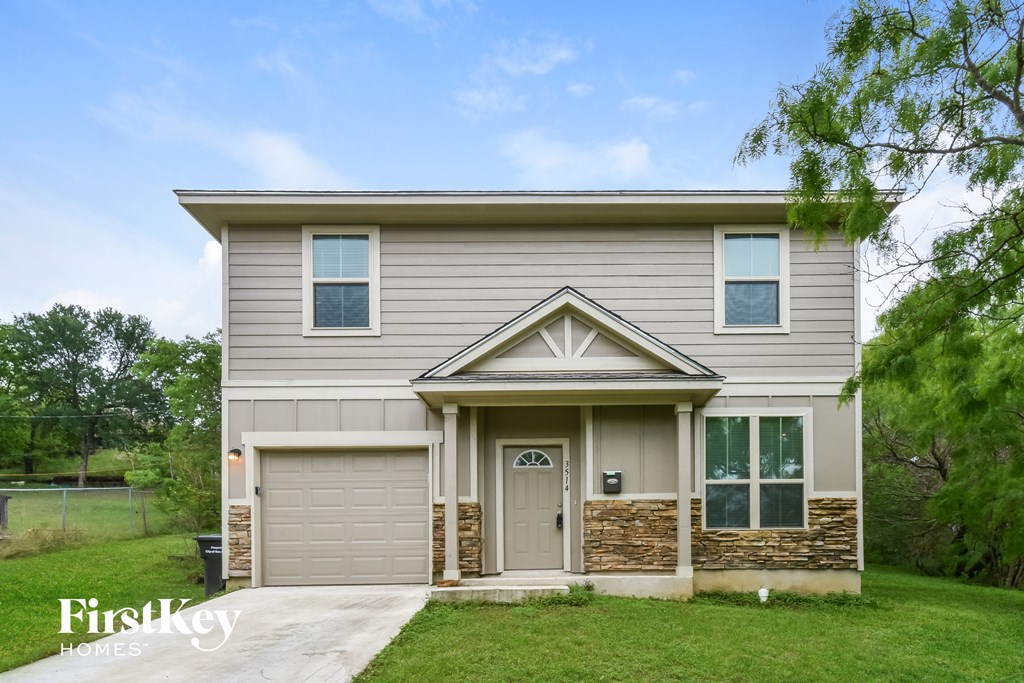A house with a garage door and a stone wall on the front.