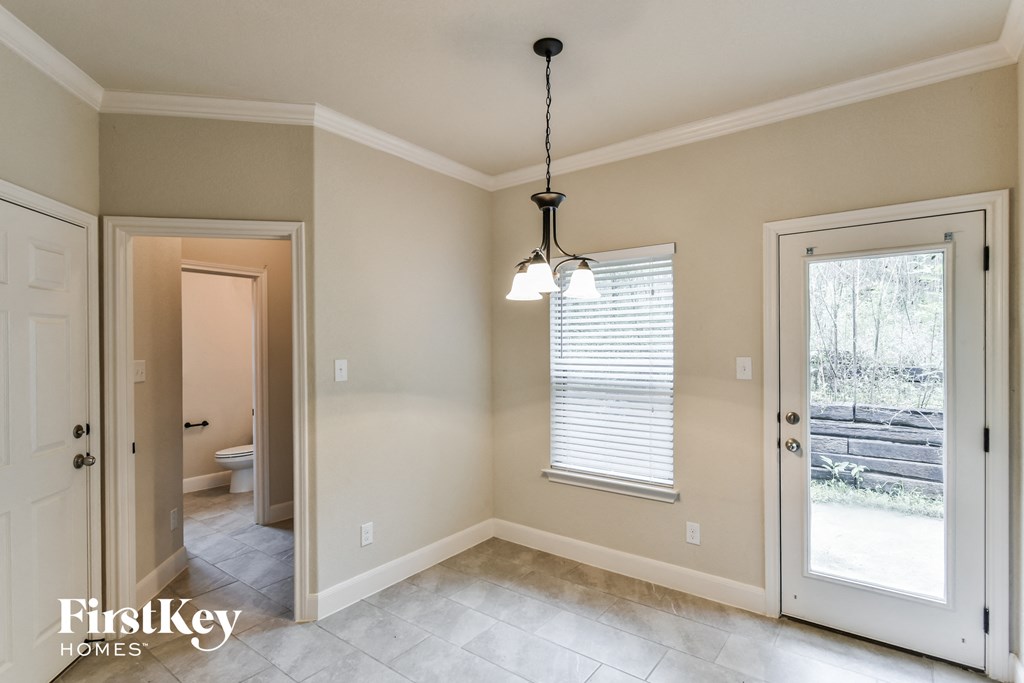 A room with a chandelier and a window with blinds.