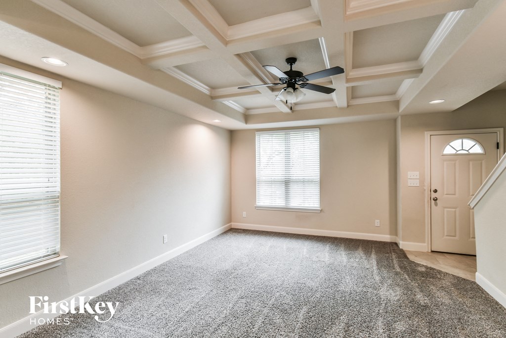 A spacious room with a ceiling fan and carpeted floor.
