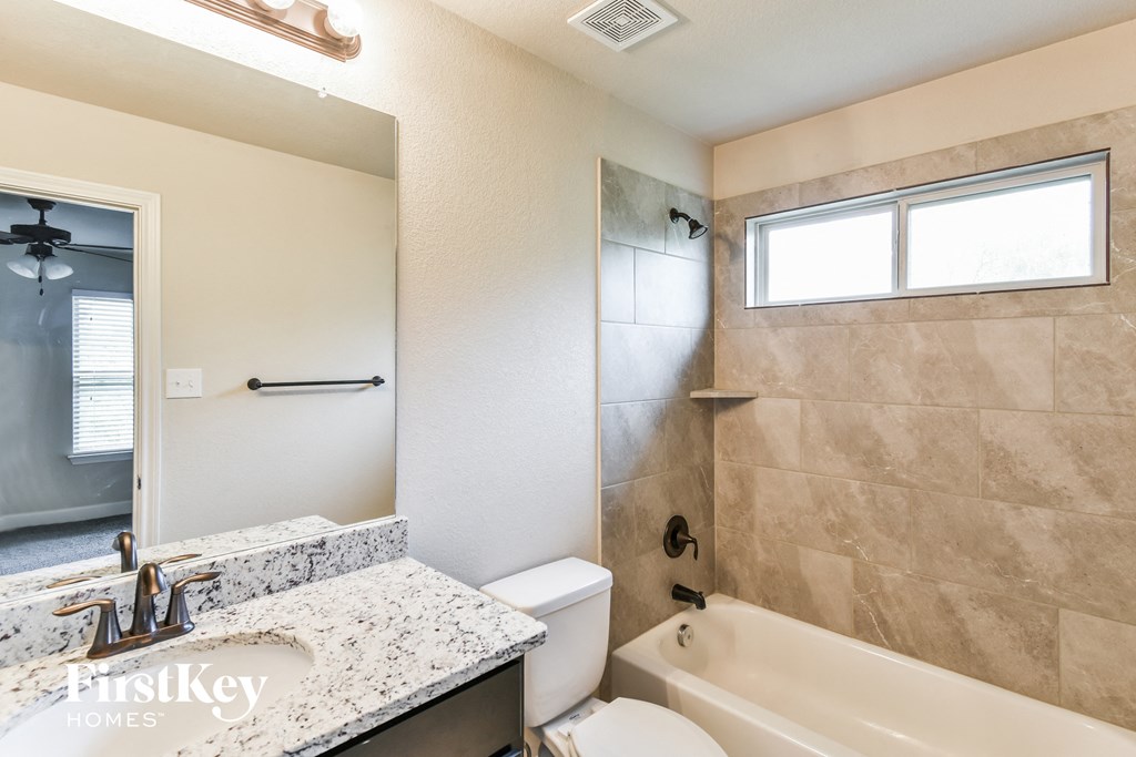 A bathroom with a marble countertop and a tiled shower area.