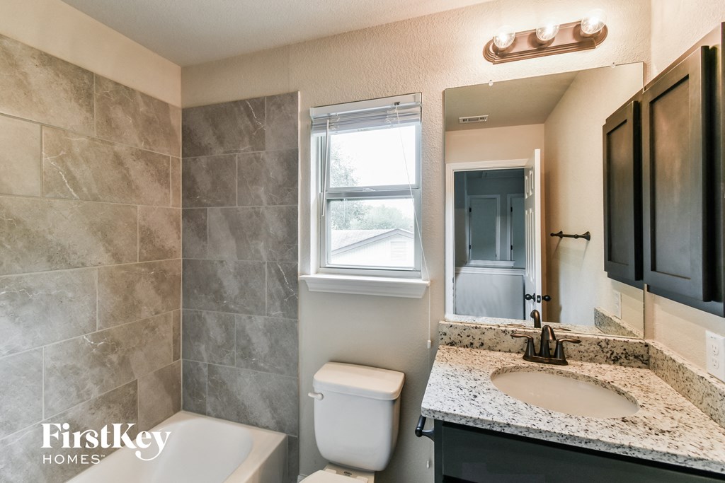 A bathroom with a marble counter top and a white toilet.