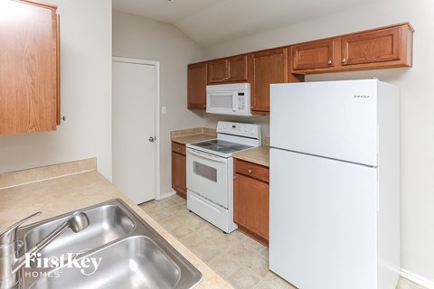 A kitchen with a white fridge, white oven, and white microwave.
