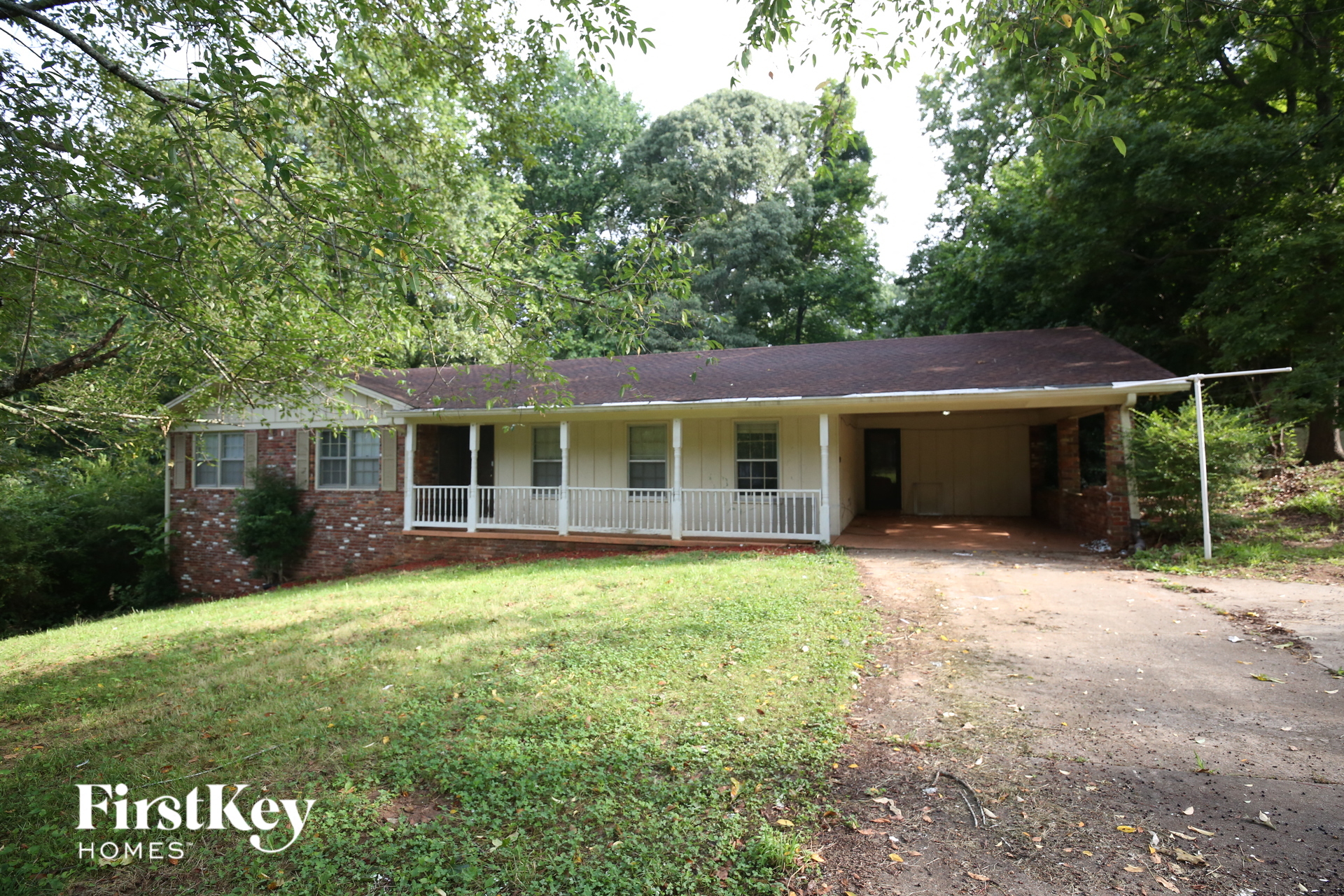the front of a brick house with a porch and a driveway