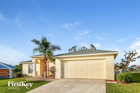 a yellow house with a garage door and a palm tree