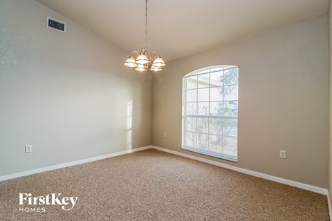 an empty dining room with a large window and a chandelier