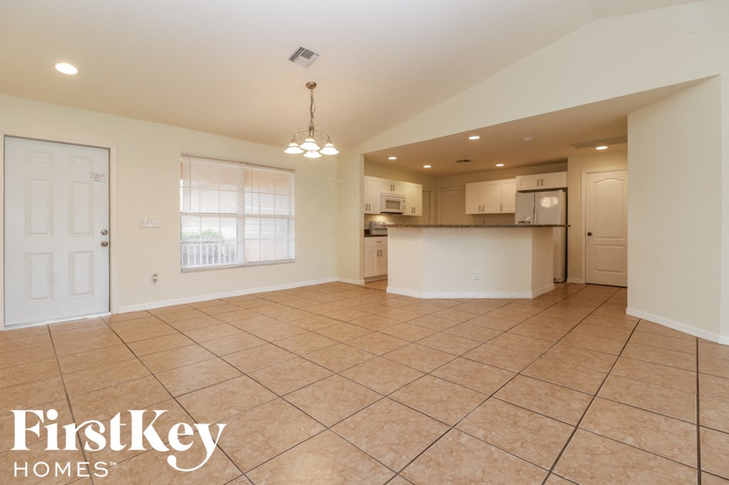 A spacious living room with a kitchen in the background.