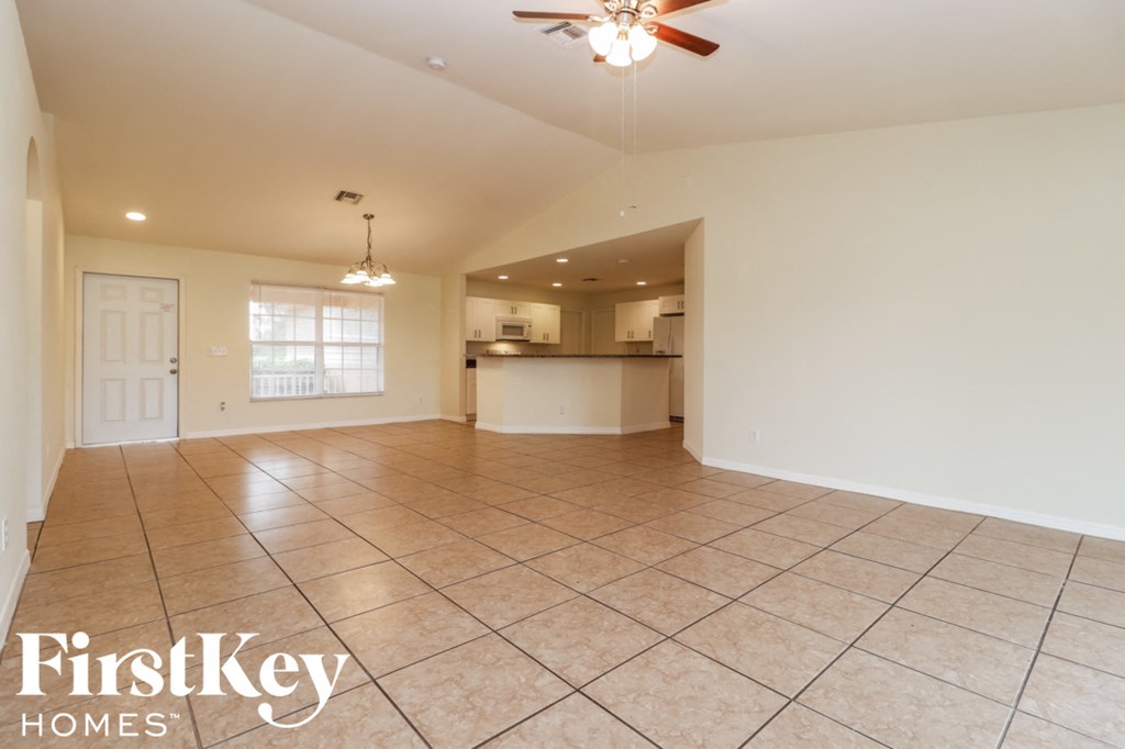 A spacious living room with a ceiling fan and tiled flooring.