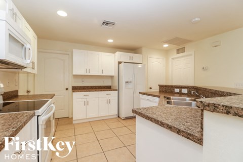 A kitchen with white cabinets and granite countertops.