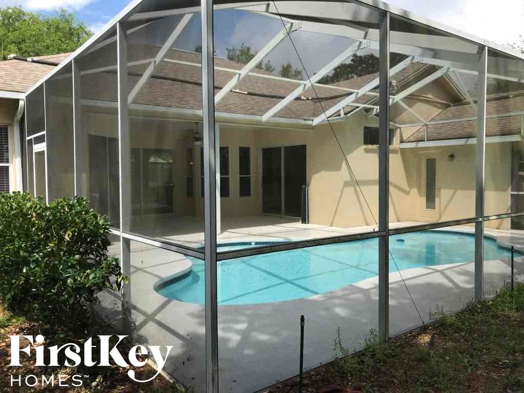 A pool in a backyard behind a glass wall.