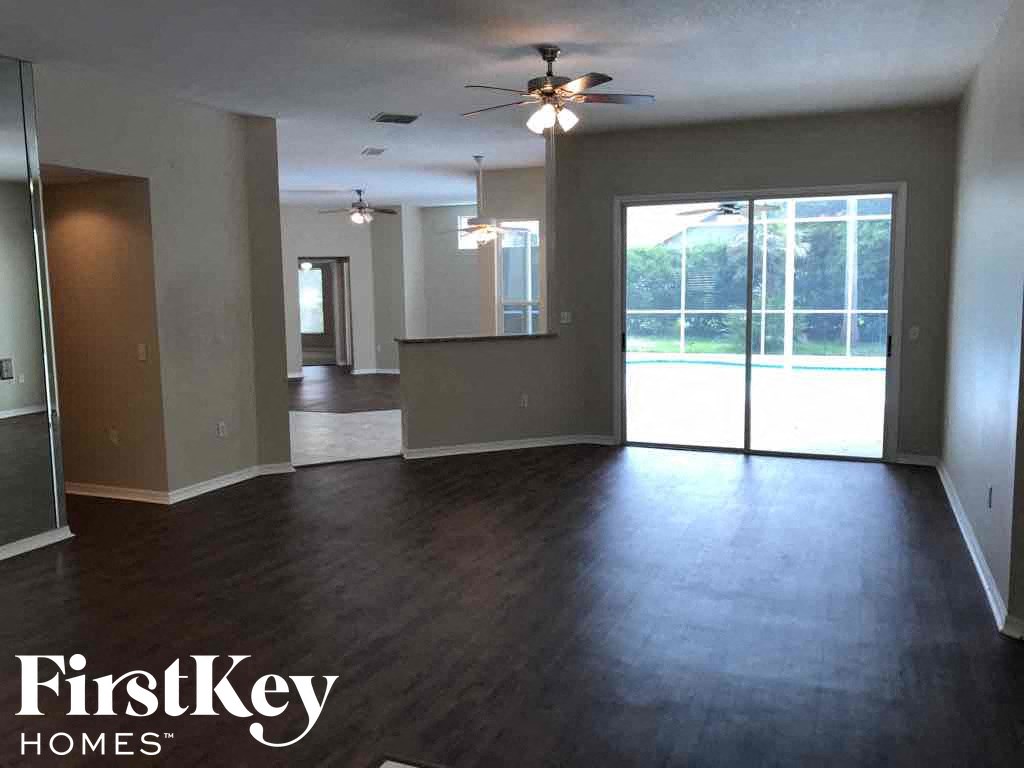 A spacious room with a ceiling fan and sliding glass doors leading to a balcony.