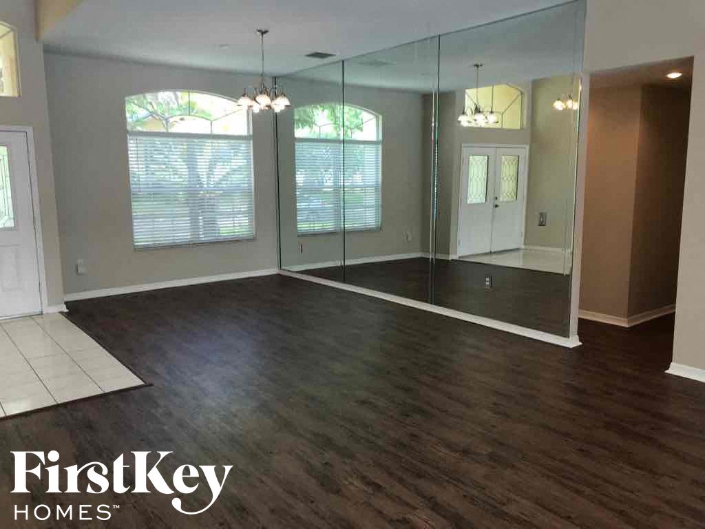 A spacious room with wood flooring and a glass wall.