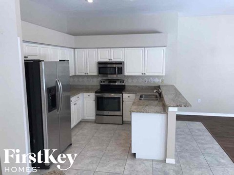 A kitchen with a refrigerator, microwave, oven, and sink.