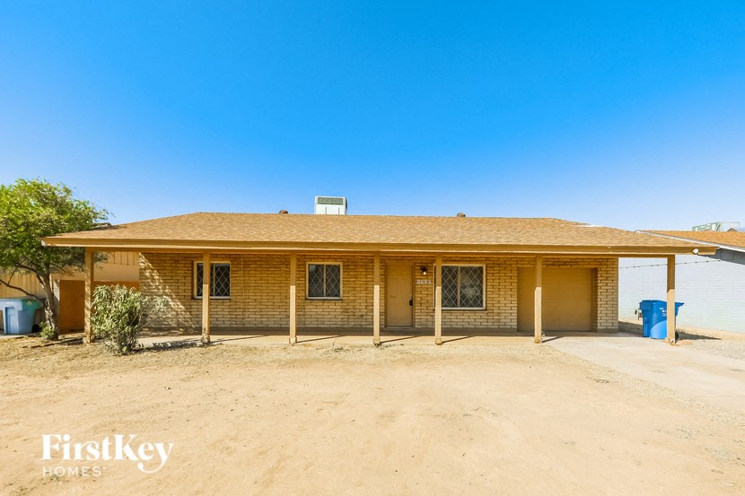 the front of a brick house with a dirt lot and a garage